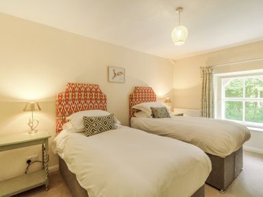 A bedroom with two single beds and patterned headboards at Gardeners Cottage in Bellingham