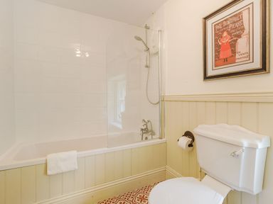 A bathroom with a bathtub a shower toilet and a framed picture on the wall at Gardeners Cottage in Bellingham