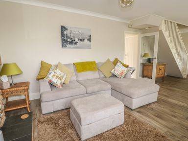 A living room with a sectional sofa and ottoman next to a side table and lamp at Bertelle in Grimston
