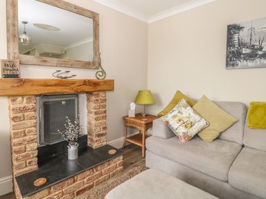 A living room with a brick fireplace a wooden mantel and a gray sofa with cushions at Bertelle in Grimston