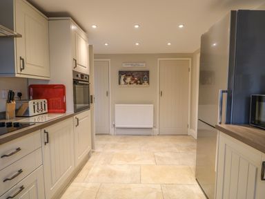 A kitchen with cabinets, an oven, a fridge, a toaster, a red tray, and two closed doors at Bertelle in Grimston