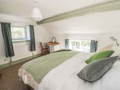 A bedroom with a bed a wooden chair a desk and two windows at Town Mill in Bewdley