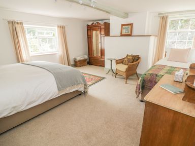 A bedroom with two beds a wicker chair an armoire and a wooden dresser at Town Mill in Bewdley