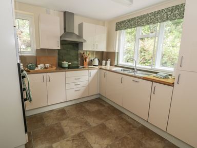 A kitchen with cream cabinets a stainless steel hood and a window with a green floral valance at Town Mill in Bewdley