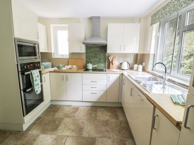 A kitchen with white cabinets a double oven a stove a sink and a window at Town Mill in Bewdley
