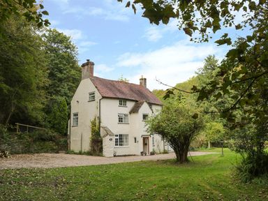 A two story house with chimneys surrounded by trees and grass at Town Mill in Bewdley