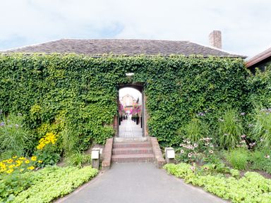 A garden entrance with ivy-covered walls and flower beds leading to a brick pathway at Town Mill in Bewdley