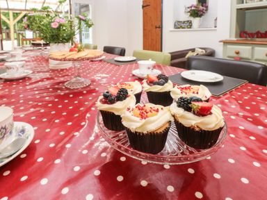 A dining table with cupcakes and a cake stand with flowers and teacups at Ty Llwyd in Nevern near Cardigan
