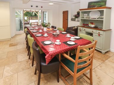 A dining room with a long table covered with a red polka dot tablecloth set with plates and cups at Ty Llwyd in Nevern near Cardigan