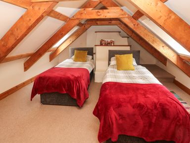 A bedroom with two single beds under wooden beams at Ty Llwyd in Nevern near Cardigan