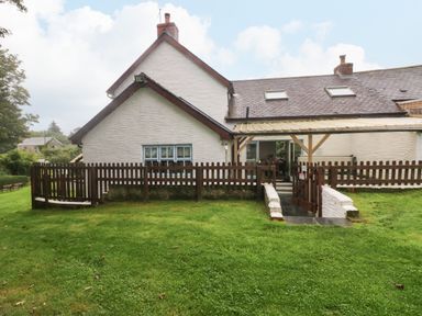 The exterior of a white house with a brown fence and a grassy yard at Ty Llwyd in Nevern near Cardigan