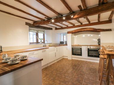 A kitchen with wooden countertops white cabinets two ovens and wooden beams on the ceiling at Lower West Curry Farmhouse in Launceston