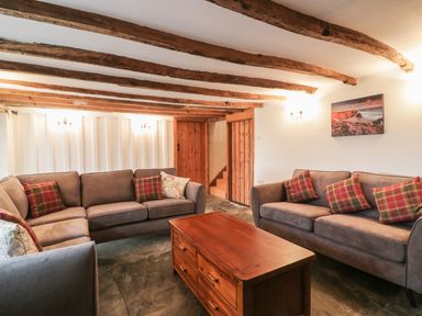 A sitting room with wooden beams on the ceiling two sofas and a wooden coffee table at Lower West Curry Farmhouse in Launceston