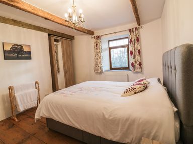 A bedroom with a large bed a wooden wardrobe a window with curtains and a towel rack at Lower West Curry Farmhouse in Launceston