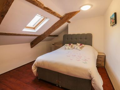 A bedroom with a skylight wooden beams a double bed and bedside tables at Lower West Curry Farmhouse in Launceston