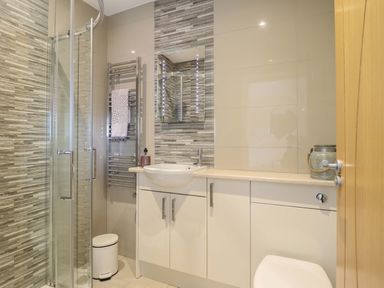 A bathroom with a shower, wash basin, and toilet at Moelfre Cottage in Llanbedr