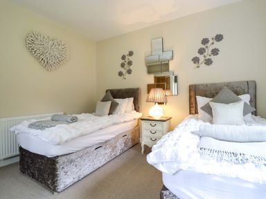 A bedroom with two beds and a lamp on a bedside table at Moelfre Cottage Llanbedr