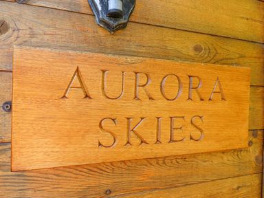 A wooden sign with the text Aurora Skies mounted on a wooden wall at Aurora Skies in Cresswell near Morpeth