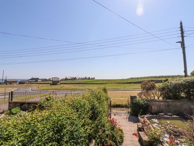A garden with hedges and flowers overlooking a road and fields at Aurora Skies in Cresswell near Morpeth