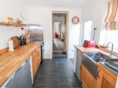 A kitchen with wooden countertops stainless steel appliances and a red toaster at Carrstone Cottage in Heacham