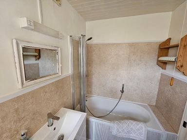 A bathroom with a bathtub sink mirror and towel at Carrstone Cottage in Heacham