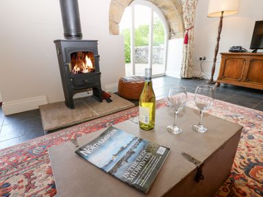A living room with a fireplace and wine glasses at Gallow Law Cottage Bellingham