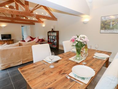 An open plan living and dining area with a dining table and sofa at Gallow Law Cottage in Bellingham