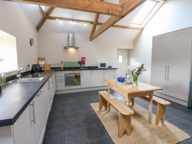 A kitchen with a dining table and flowers at Gallow Law Cottage in Bellingham