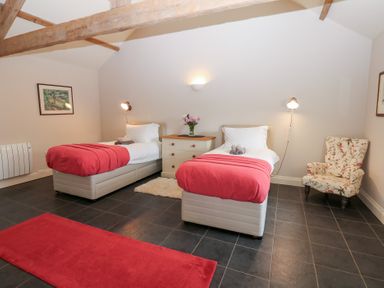 A bedroom with two beds and a chair at Gallow Law Cottage in Bellingham