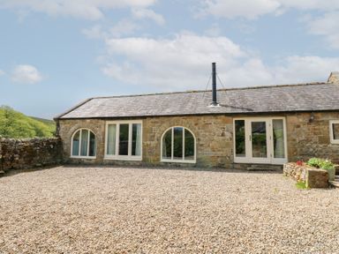 An exterior view of a cottage with stone walls and windows at Gallow Law Cottage in Bellingham