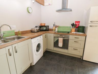 A kitchen with appliances and cabinets at Shepherds Burn Cottage in Bellingham