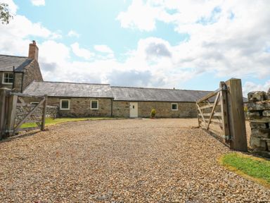 An outdoor area with a gravel driveway and a stone building at Shepherds Burn Cottage Bellingham