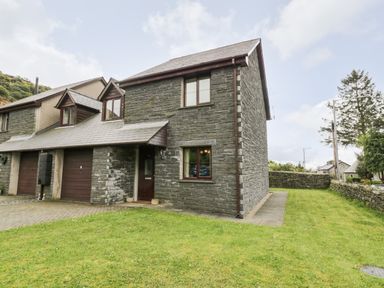 A stone house with a small front yard and garage in Manod near Blaenau Ffestiniog