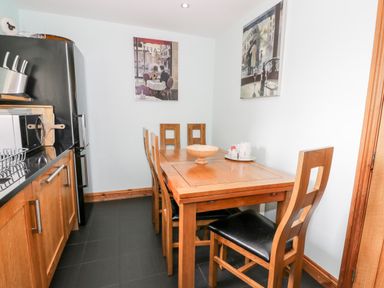 A dining area with a wooden table and six chairs in a kitchen at 6 Stad Yr Ysgol Manod near Blaenau Ffestiniog