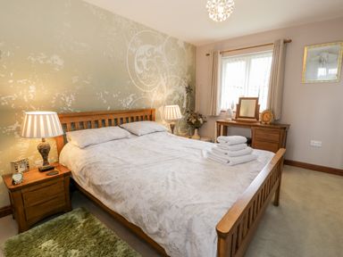 A bedroom with a wooden bed and bedside tables with lamps at 6 Stad Yr Ysgol in Manod near Blaenau Ffestiniog