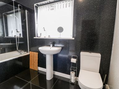 A bathroom with a white sink pedestal toilet bathtub and a window at 6 Stad Yr Ysgol in Manod near Blaenau Ffestiniog