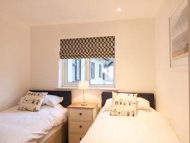 A bedroom with two single beds separated by a nightstand with a lamp at Keepers Cottage in Sidmouth