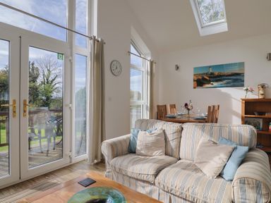 A living room with a sofa and dining area at Keepers Cottage in Sidmouth