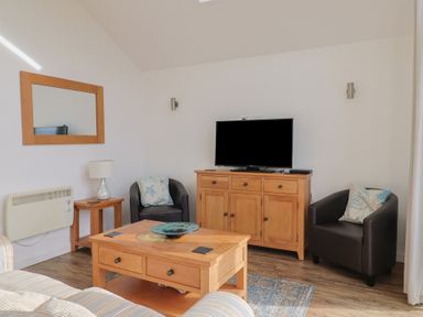 A living room with a television and furniture at Keepers Cottage in Sidmouth