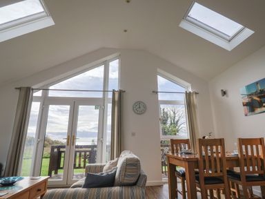A living room with a dining area and large windows at Keepers Cottage in Sidmouth