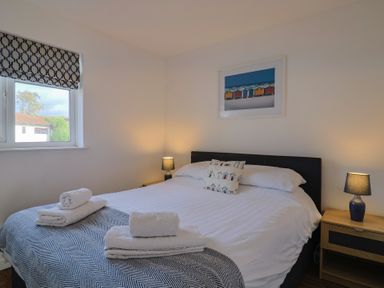 A bedroom with a bed, lamps, and window at Keepers Cottage in Sidmouth