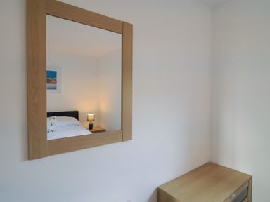 A bedroom with a bed and lamp visible in the mirror at Keepers Cottage Sidmouth