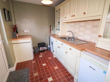 A utility room with a double sink washing machine and small freezer at Rosies Cottage in Bushmills County Antrim