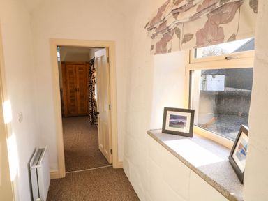 A hallway with a window and framed pictures on the sill at Rosies Cottage in Bushmills County Antrim