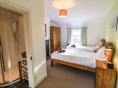 A bedroom with two single beds wooden furniture and an en suite shower at Rosies Cottage in Bushmills County Antrim