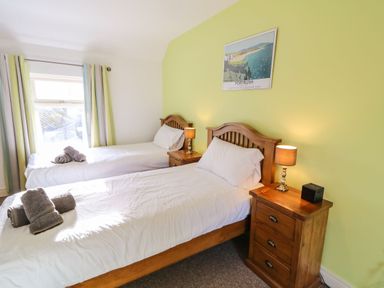 A bedroom with two single beds bedside tables and lamps at Rosies Cottage in Bushmills County Antrim