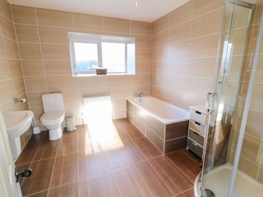 A bathroom with a toilet sink bathtub shower and window at Rosies Cottage in Bushmills County Antrim