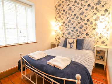 A bedroom with a double bed two bedside tables and floral wallpaper at Siskin in Dinas Mawddwy near Dolgellau