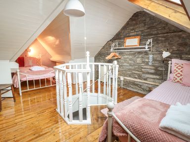 A bedroom with two single beds wooden floor and spiral staircase at Siskin in Dinas Mawddwy near Dolgellau