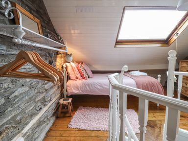 A bedroom with a single bed with pillows a skylight window a wooden floor and a stone wall at Siskin in Dinas Mawddwy near Dolgellau